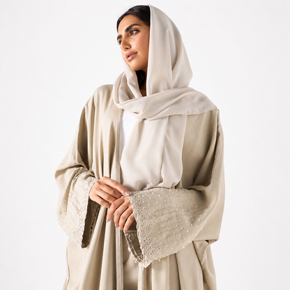 Close-up of pearl embellishments on beige bisht abaya sleeve