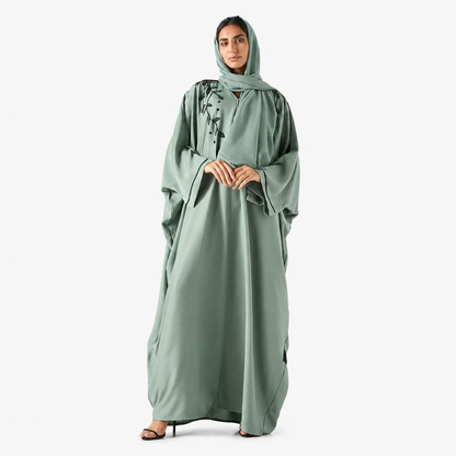 Close-up of black shoulder embroidery on sage green bisht abaya